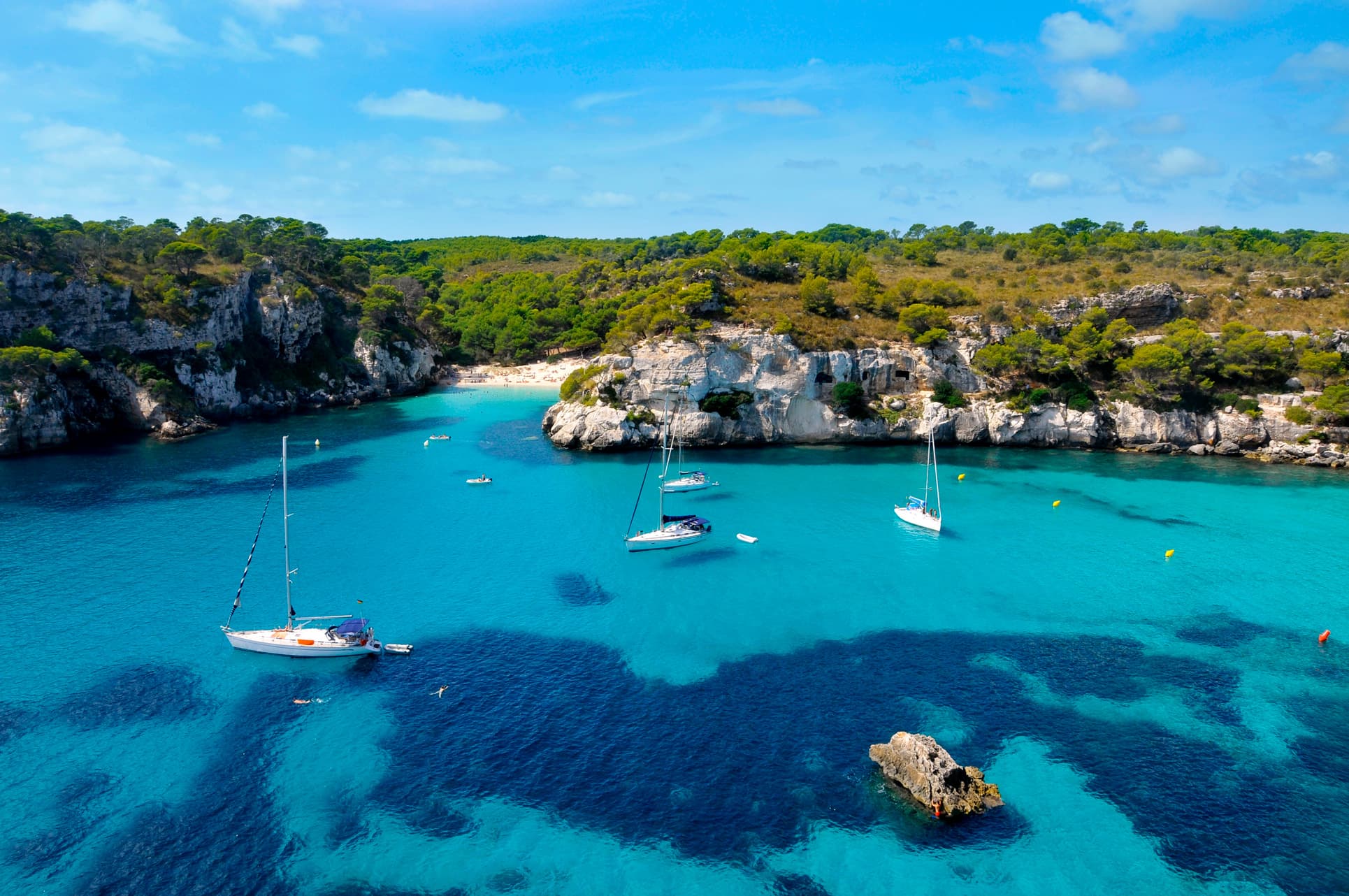 Cala de aguas turquesa rodeada de acantilados y pinar en Menorca